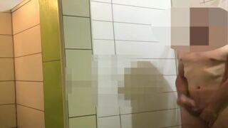 A men wanks in public shower while people wait for showering