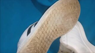 "A pair of white Adidas sneakers worn by a beautiful preppy girl."