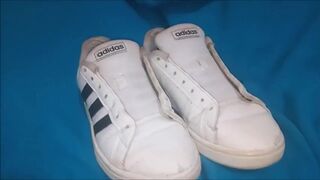 "A pair of white Adidas sneakers worn by a beautiful preppy girl."