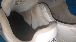 "A pair of white Adidas sneakers worn by a beautiful preppy girl."