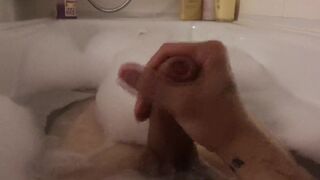 The guy jerks off taking a bath with foam